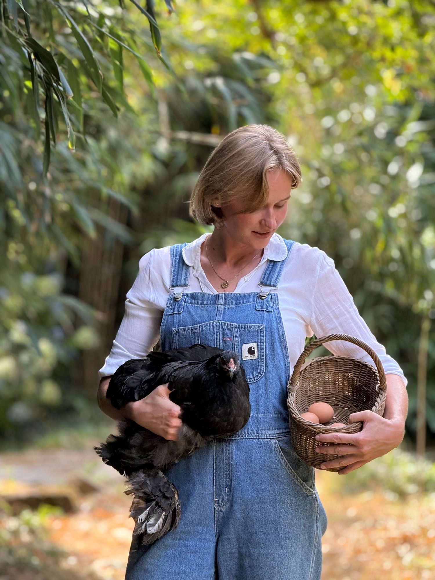 Alizé Foveau tenant une poule noire, un panier d’œufs à la main.